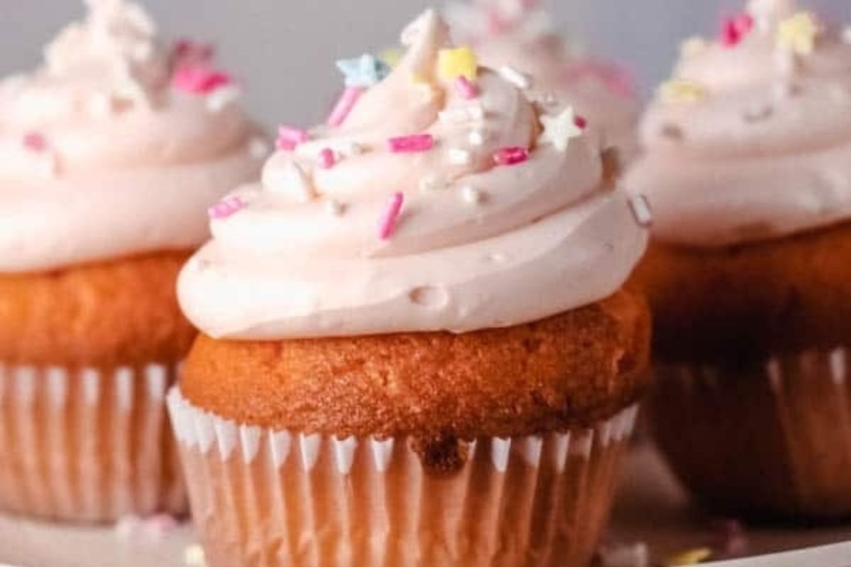 Pink cupcakes with sprinkles on a white plate, perfect for pink recipes.