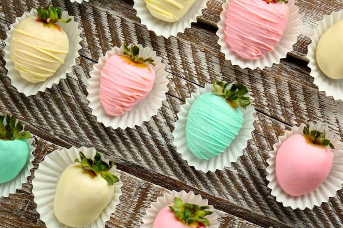A group of frosted strawberries in various shades of pink on a wooden table.