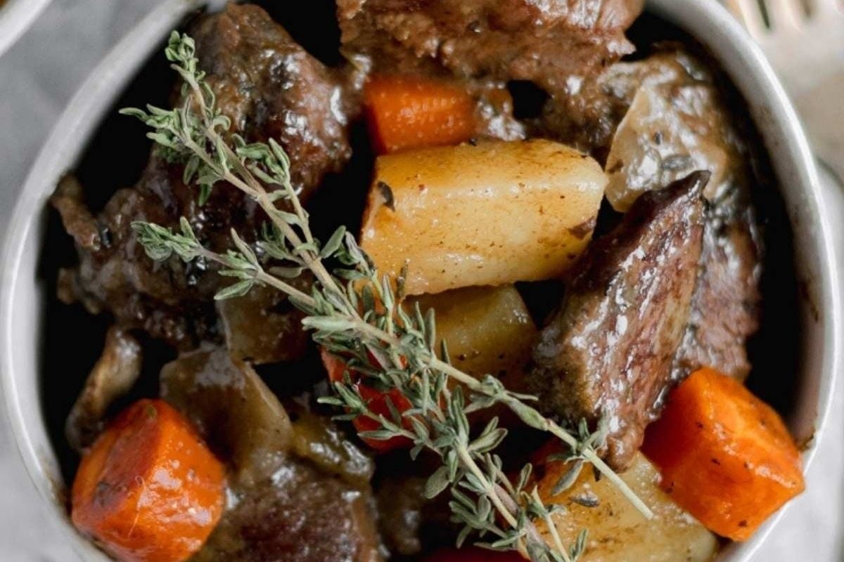 A wholesome bowl of slow cooker beef stew with carrots and sprigs of thyme.