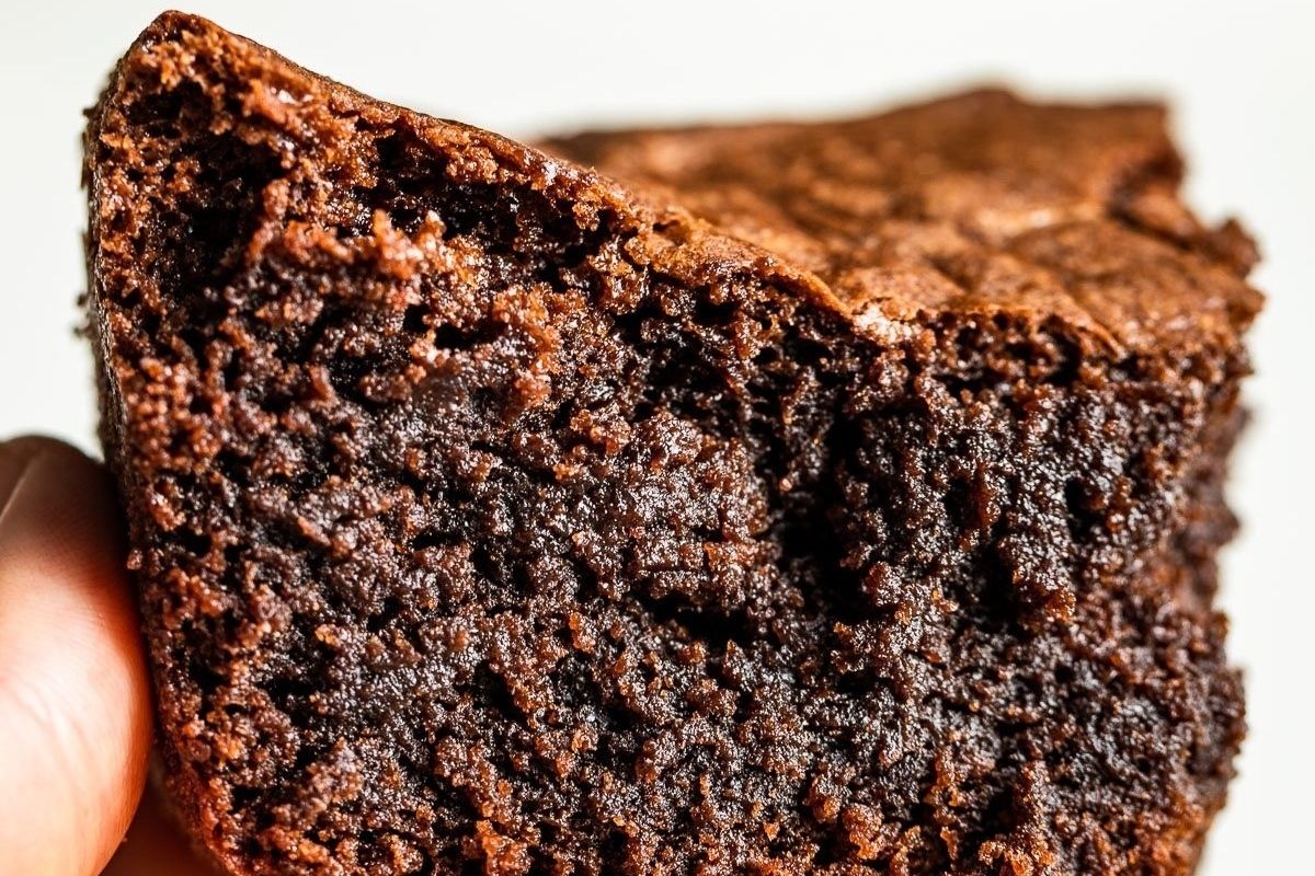 A person holding up a tempting Valentine's dessert, a chocolate brownie.
