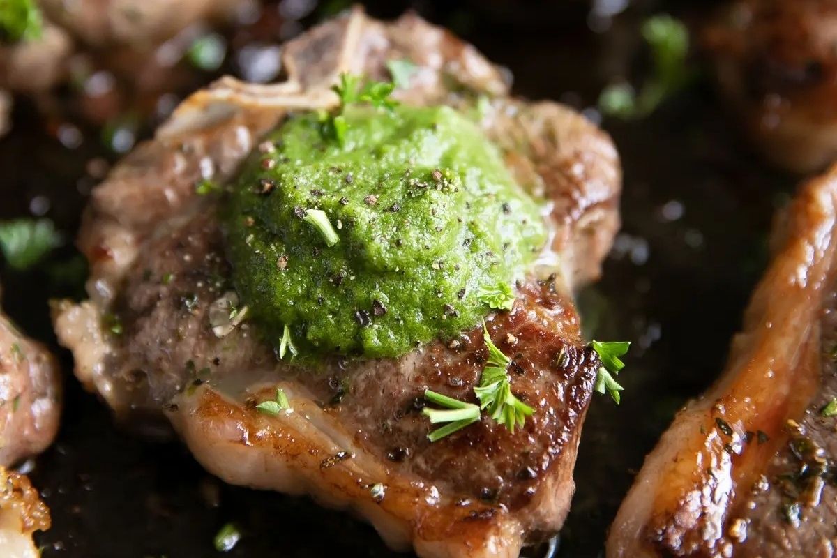 A cooked steak topped with green herb butter and garnished with chopped parsley, perfect for a romantic Valentine's Date Night Dinner.