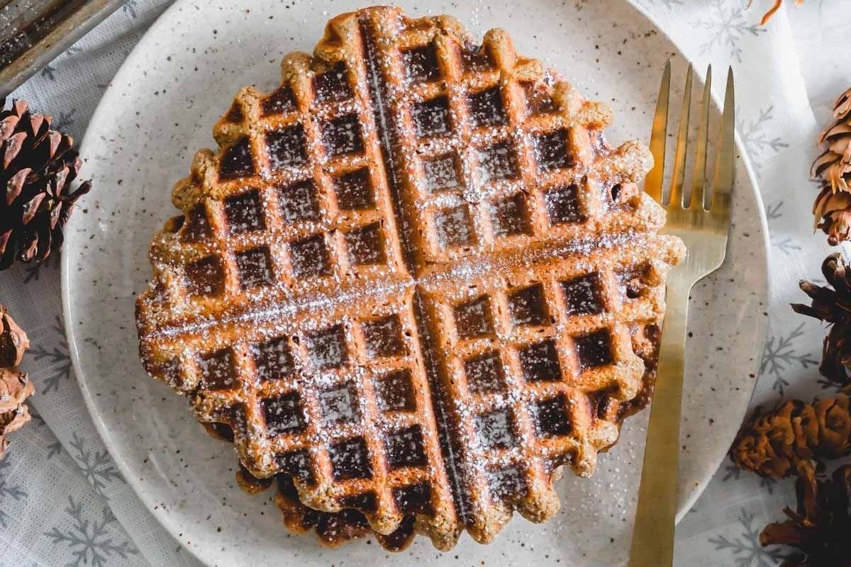 Delicious waffles topped with powdered sugar served on a plate, accompanied by rustic pine cones.