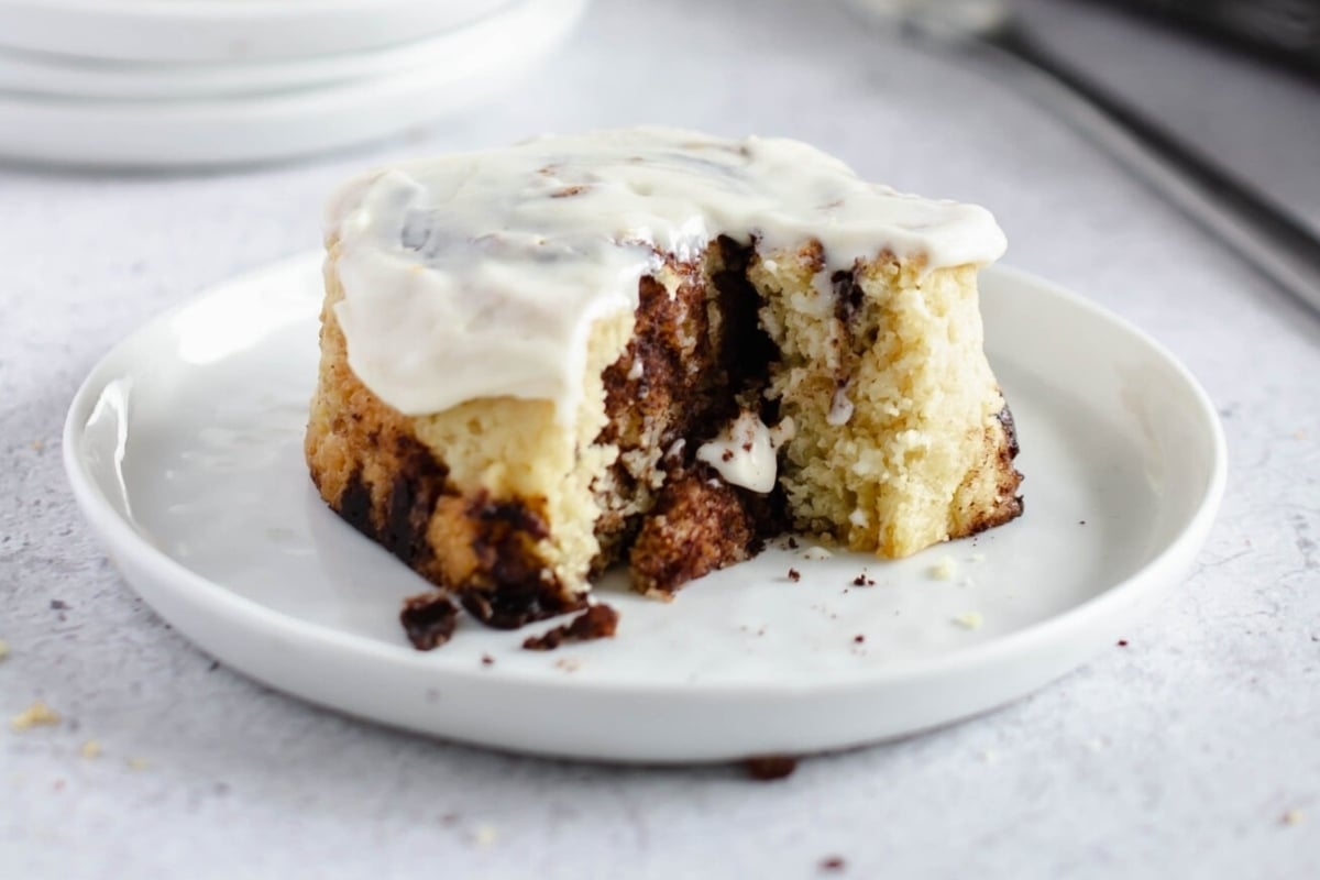A mouthwatering cinnamon roll with rich icing tantalizingly presented on a plate.