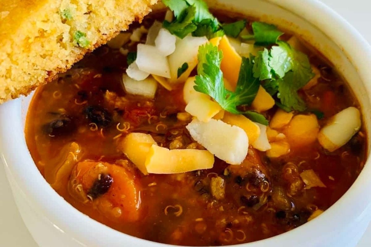 A wholesome bowl of chili with cornbread next to it, slow-cooked to perfection.