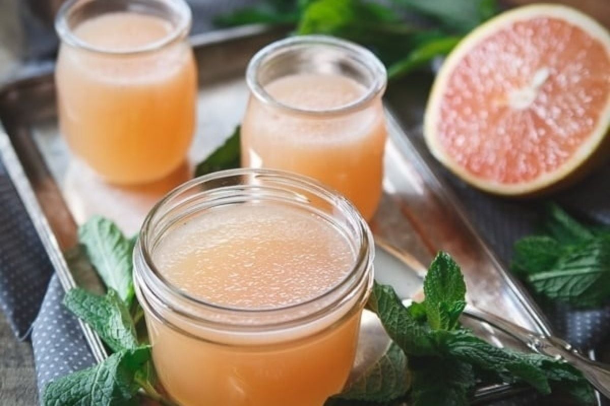Two jars of grapefruit juice with mint leaves on a tray, perfect for refreshing citrus recipes.