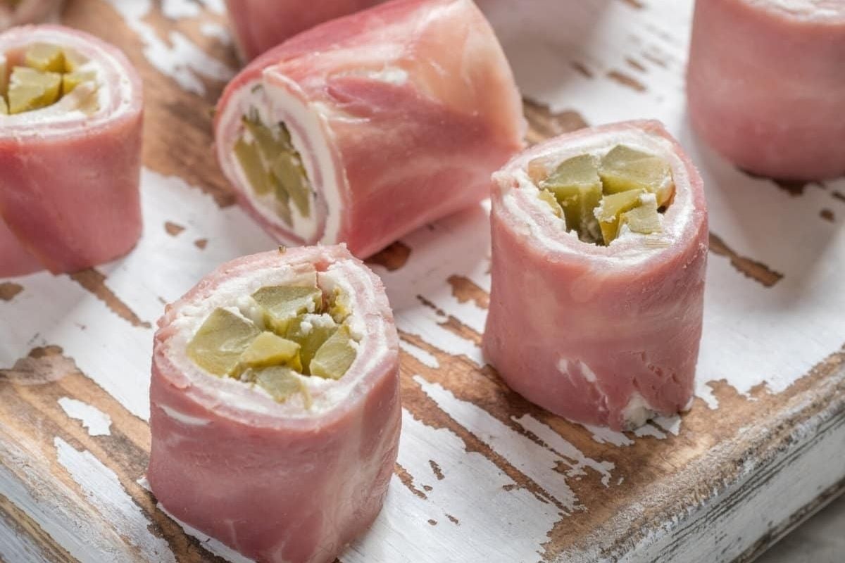 Ham wrapped in bacon on a wooden cutting board.