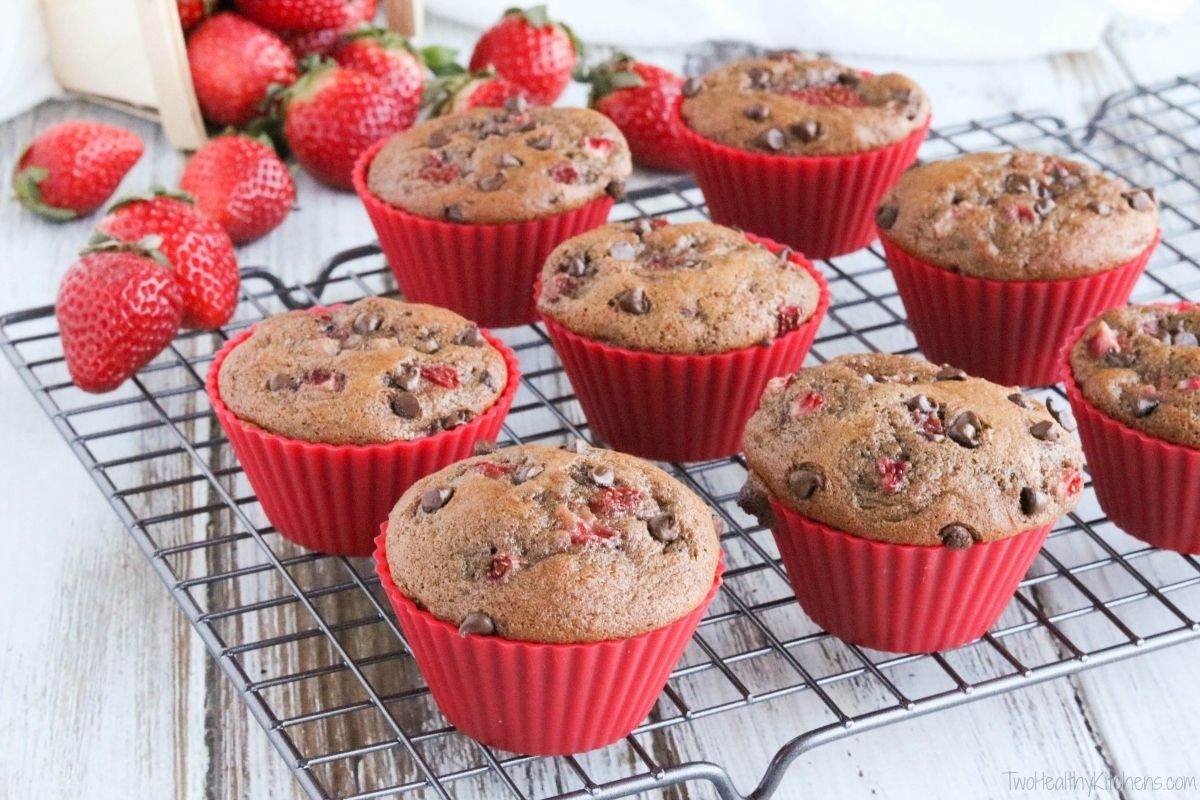 Chocolate chip and strawberry muffins in red silicone cups on a cooling rack, with fresh strawberries nearby—perfect for Valentine’s breakfasts for kids.
