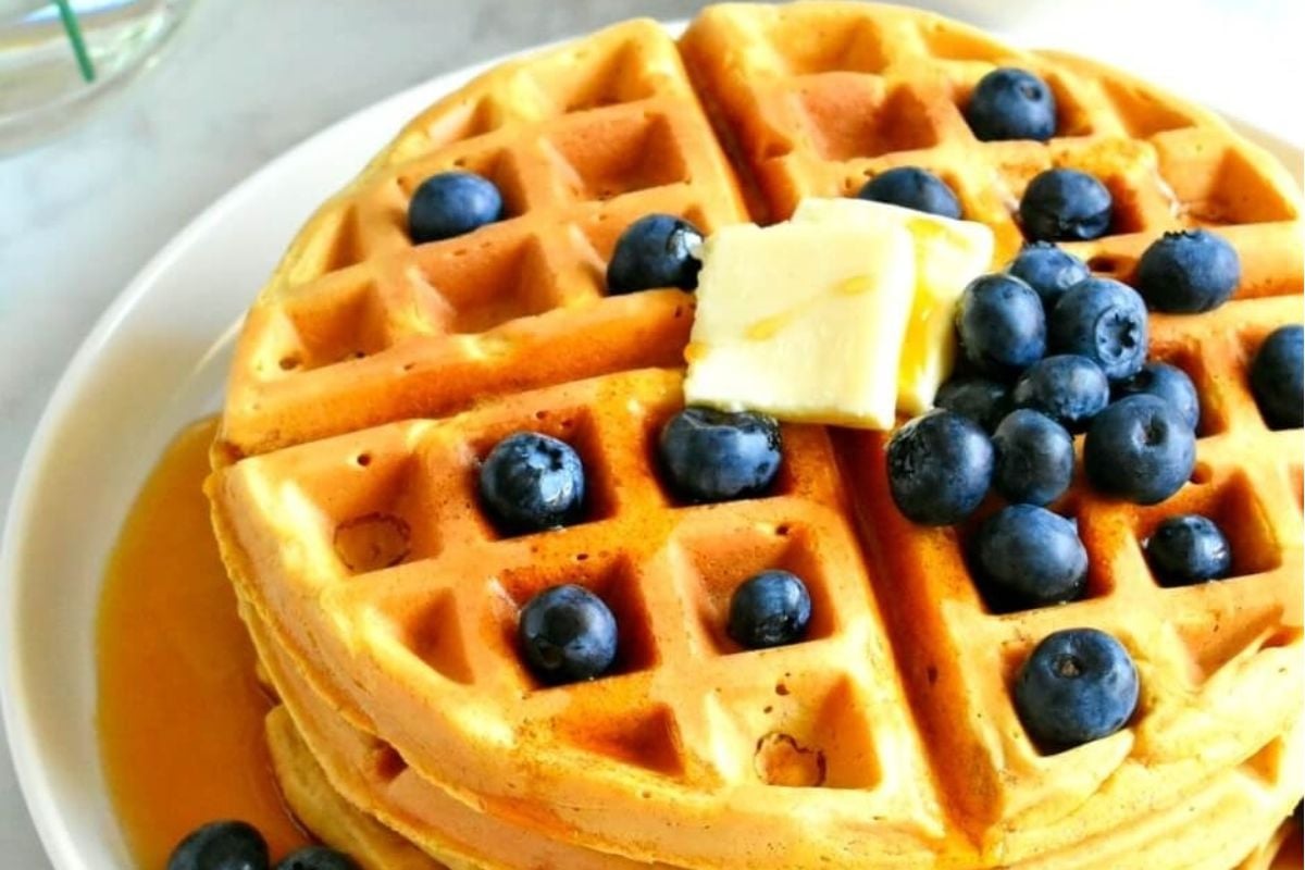 Delicious waffles topped with blueberries and a pat of butter on a plate.
