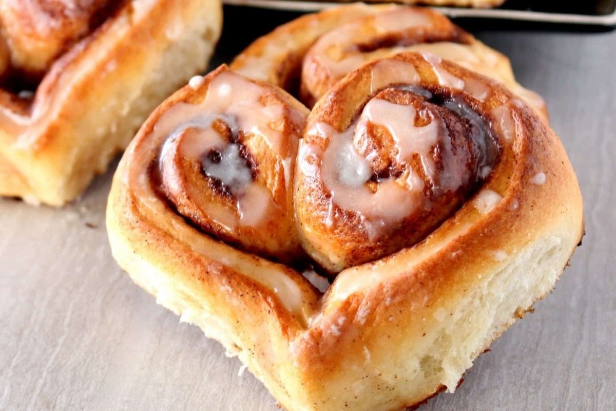 Heart-shaped cinnamon rolls on a baking sheet, transforming breakfast into a delightful heart-shaped treat.