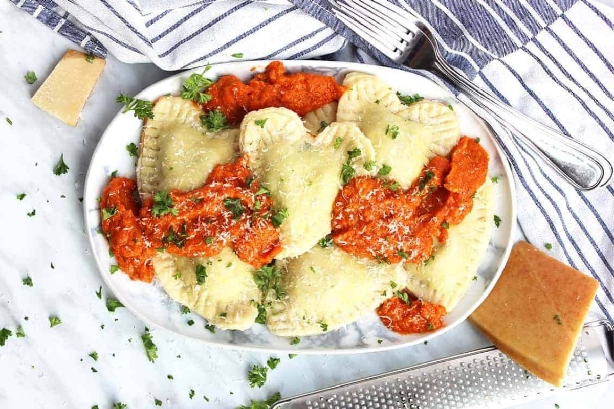A plate of heart-shaped ravioli with sauce and cheese.
