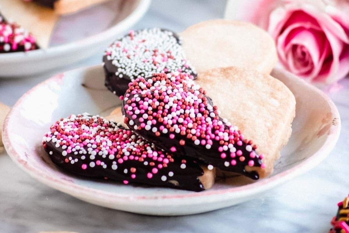 Heart-shaped cookies with sprinkles on a plate.