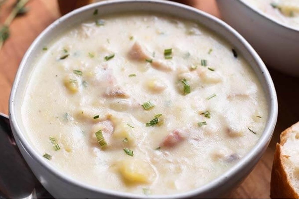 A tasty bowl of chowder with ham and potatoes.