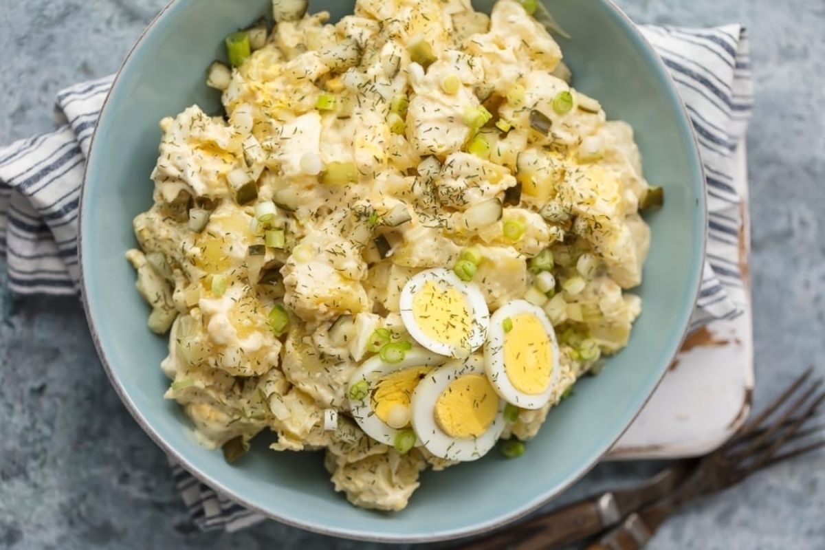 A flavorful bowl of potato salad with eggs and green onions, perfect for pickle lovers.