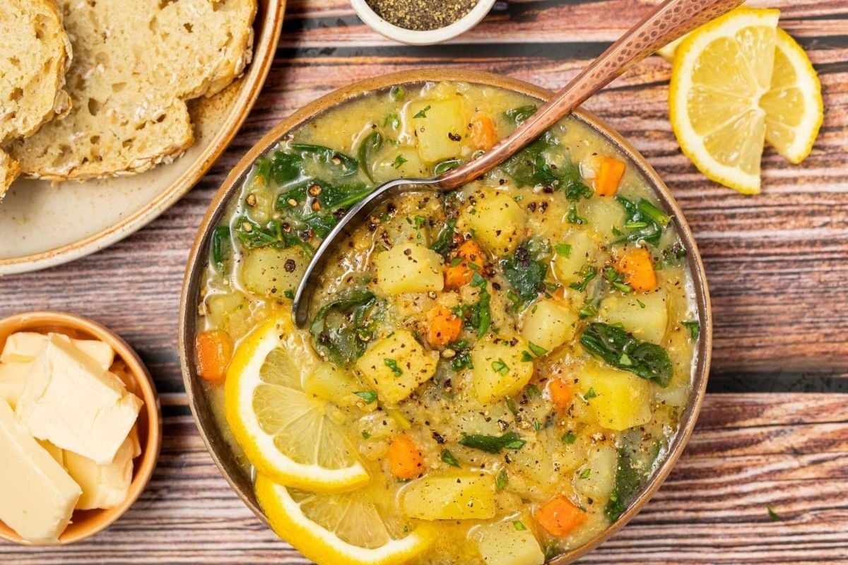 A warm bowl of winter soup and a slice of fresh bread placed on a rustic wooden table.