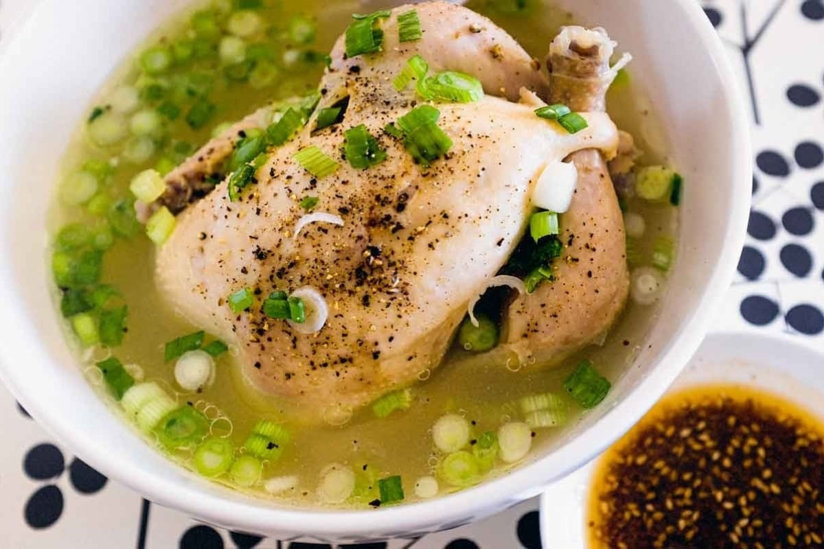 A bowl of delicious chicken soup with green onions and sesame seeds, made using a flavorful chicken soup recipe.