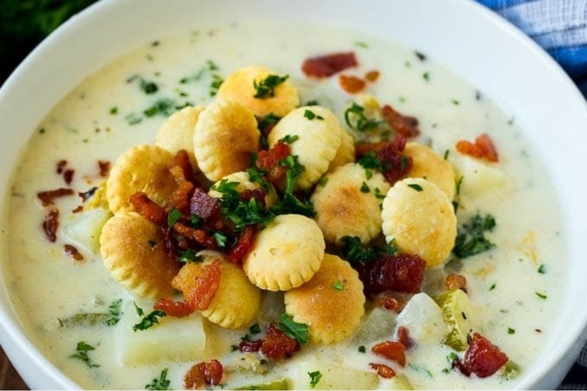 A creamy bowl of chowder with crackers and bacon.