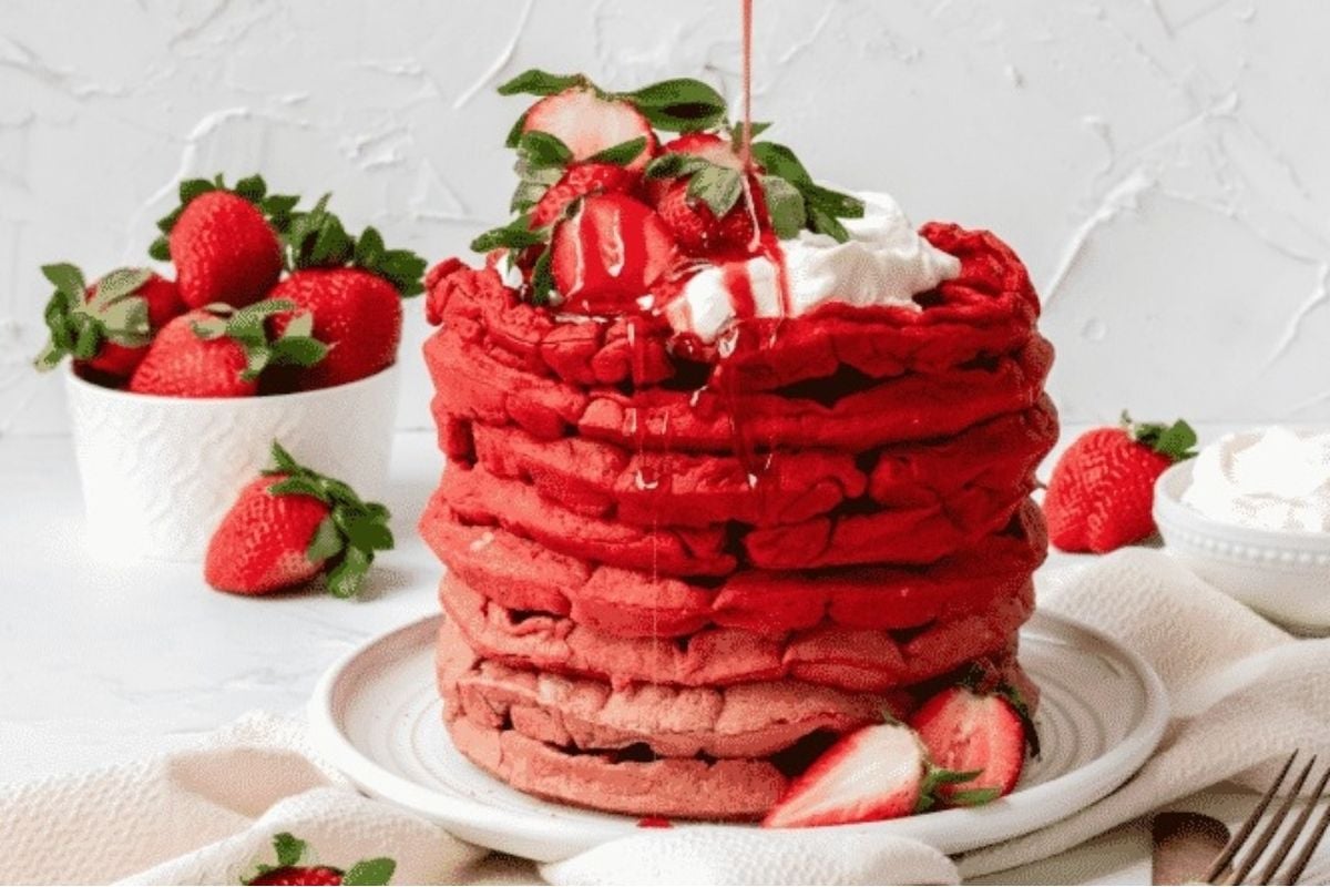 A stack of strawberry pancakes on a plate.