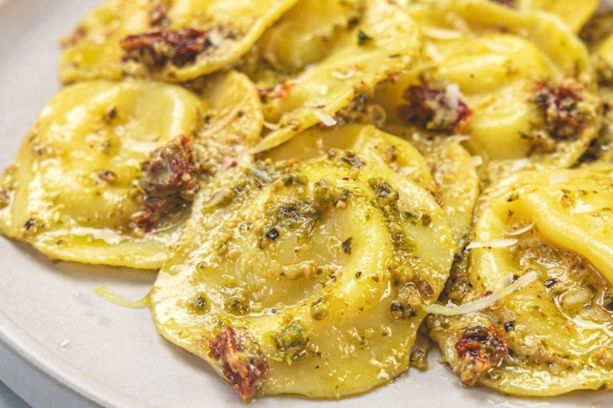 A plate of stuffed tortellini with pesto, perfect for ravioli lovers.