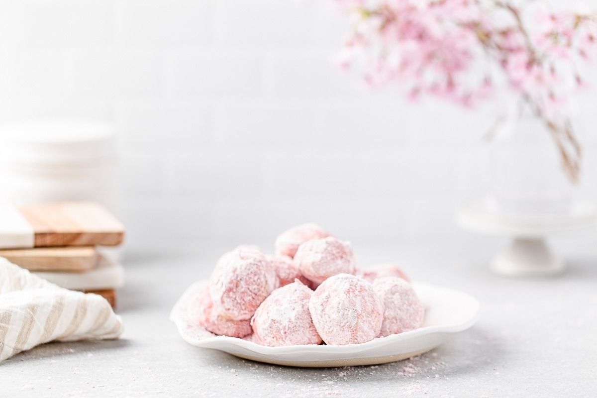 Pink powdered sugar cookies on a white plate.