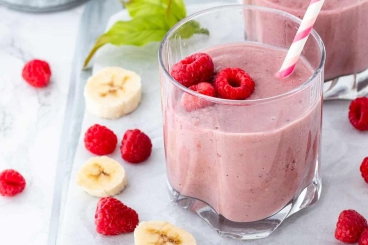 Two glasses of smoothie with raspberries, bananas, and pinwheel recipes.