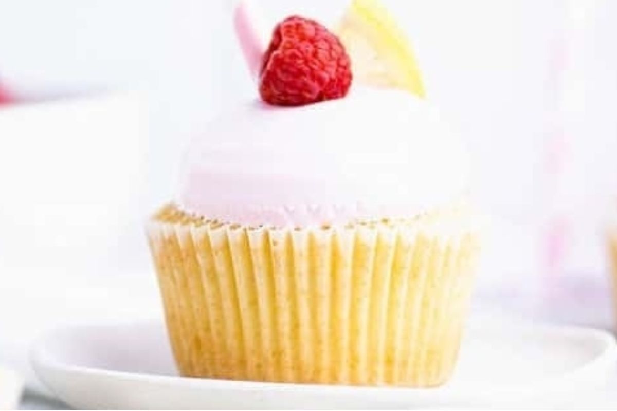 A pink cupcake with a raspberry on top.