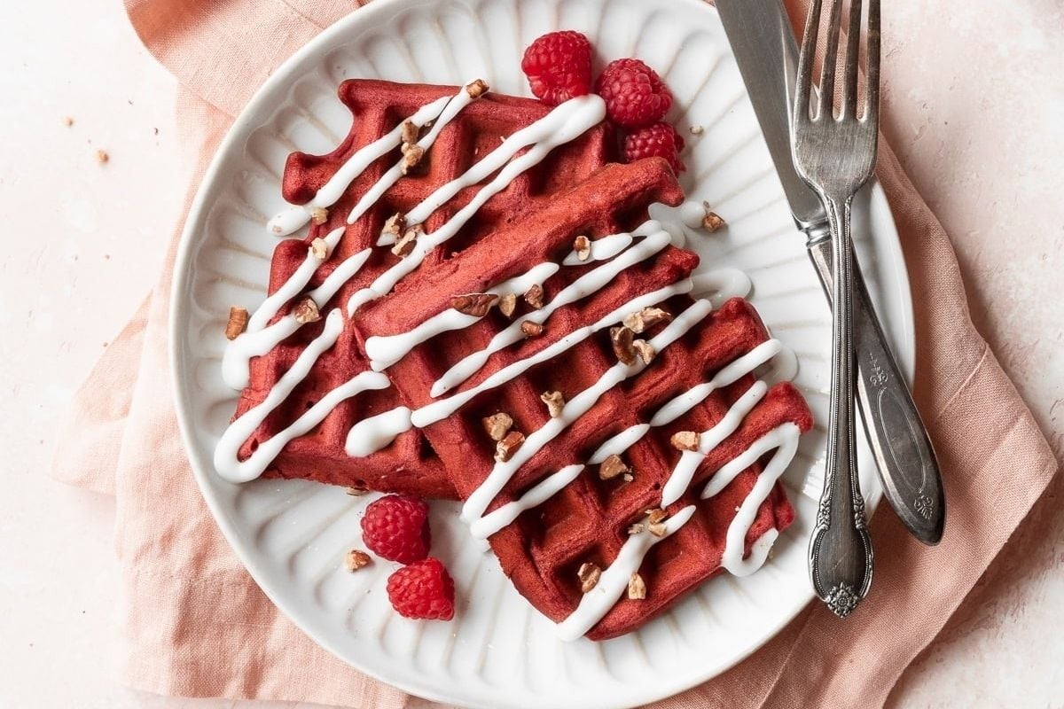         Try this delicious and indulgent red velvet waffle recipe topped with fluffy whipped cream and juicy raspberries.