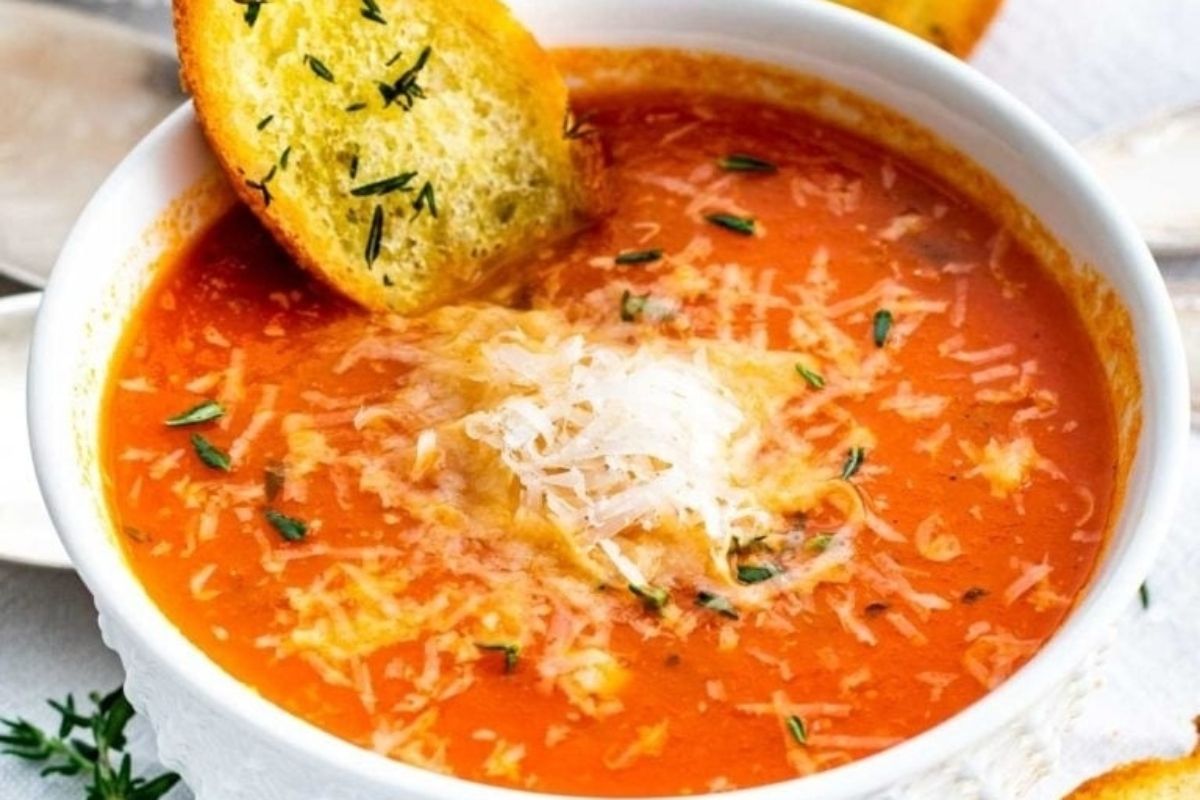 A tomato-based soup with a piece of bread.