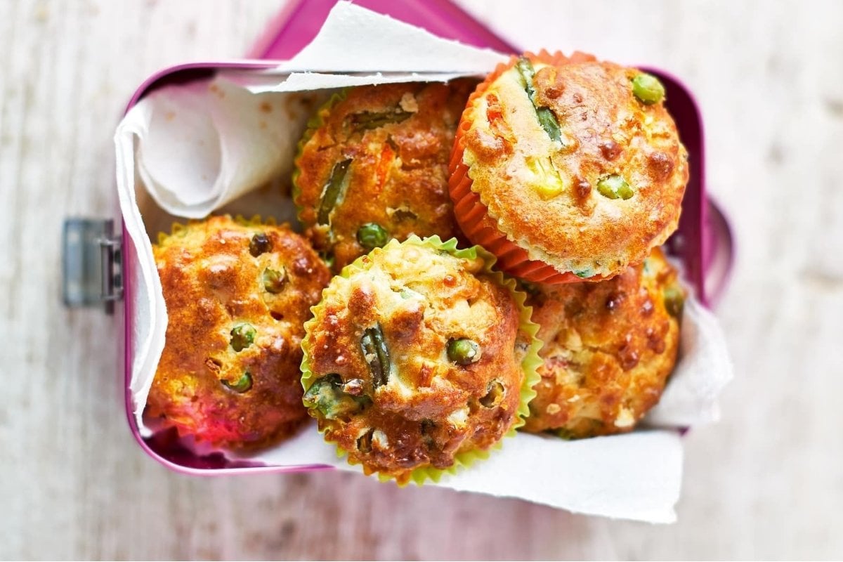Savory muffins with green vegetables in a pink lunch box.