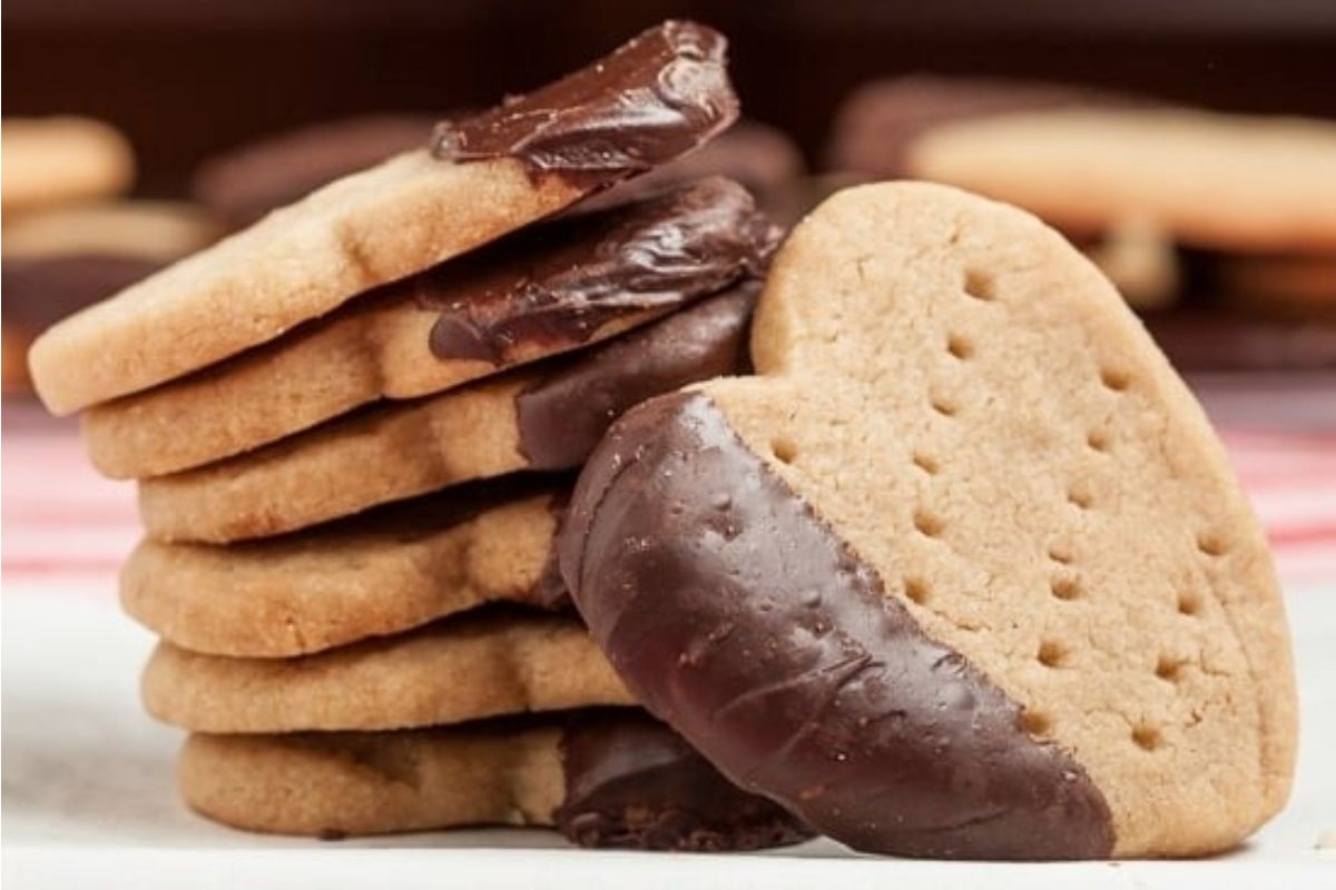 A stack of heart-shaped cookies with chocolate covered cookies.