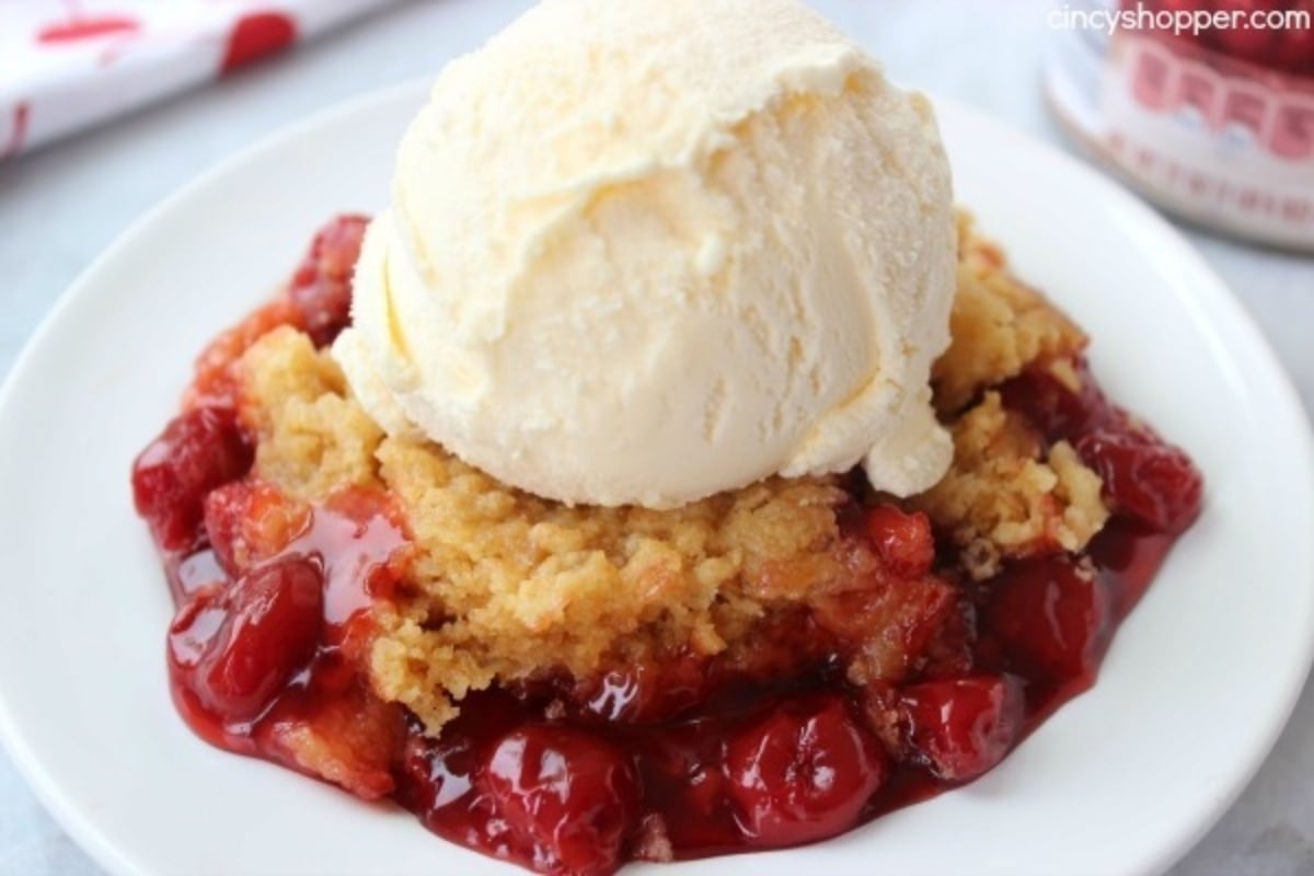 Cherry dump cake with ice cream on a plate.