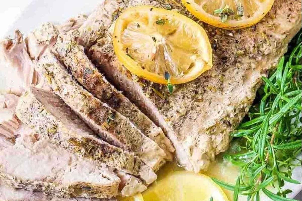 Pork tenderloin with lemon on a white plate.