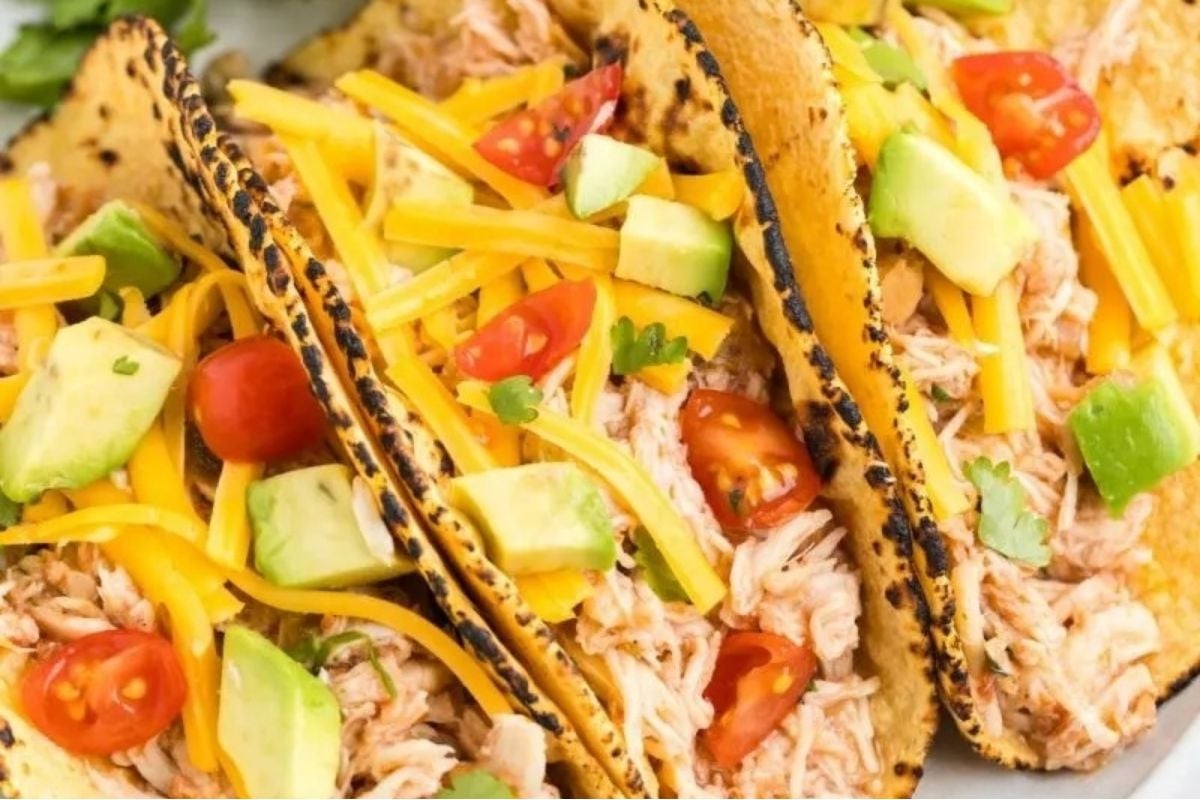 Wholesome chicken tacos on a plate with tomatoes and avocado.