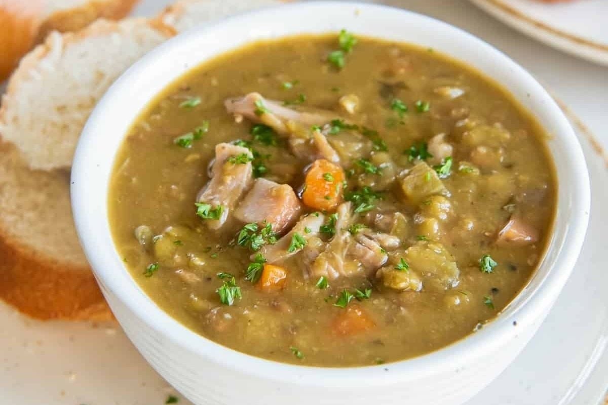 A wholesome bowl of soup with bread next to it.