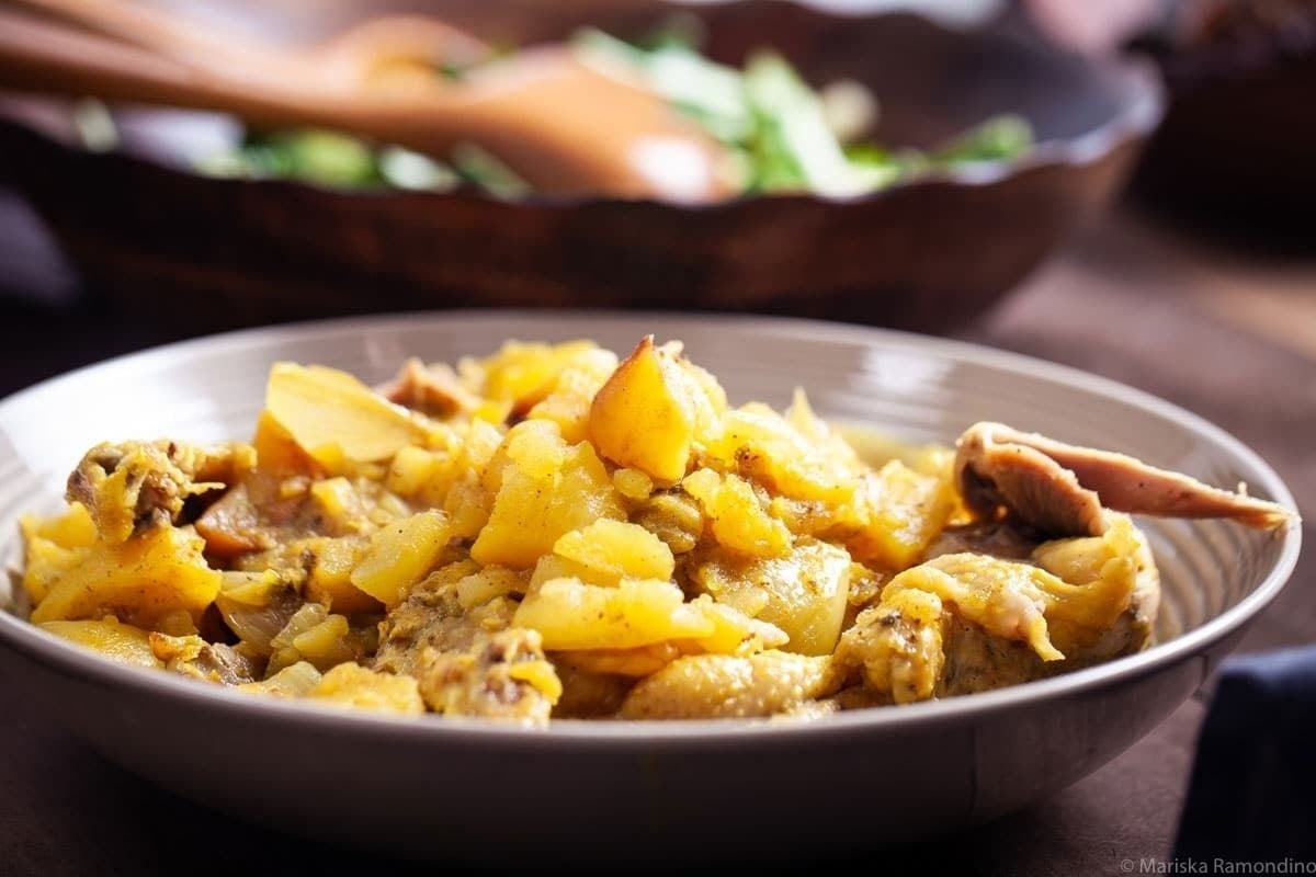 A wholesome bowl of slow cooker chicken and potato curry on a wooden table.