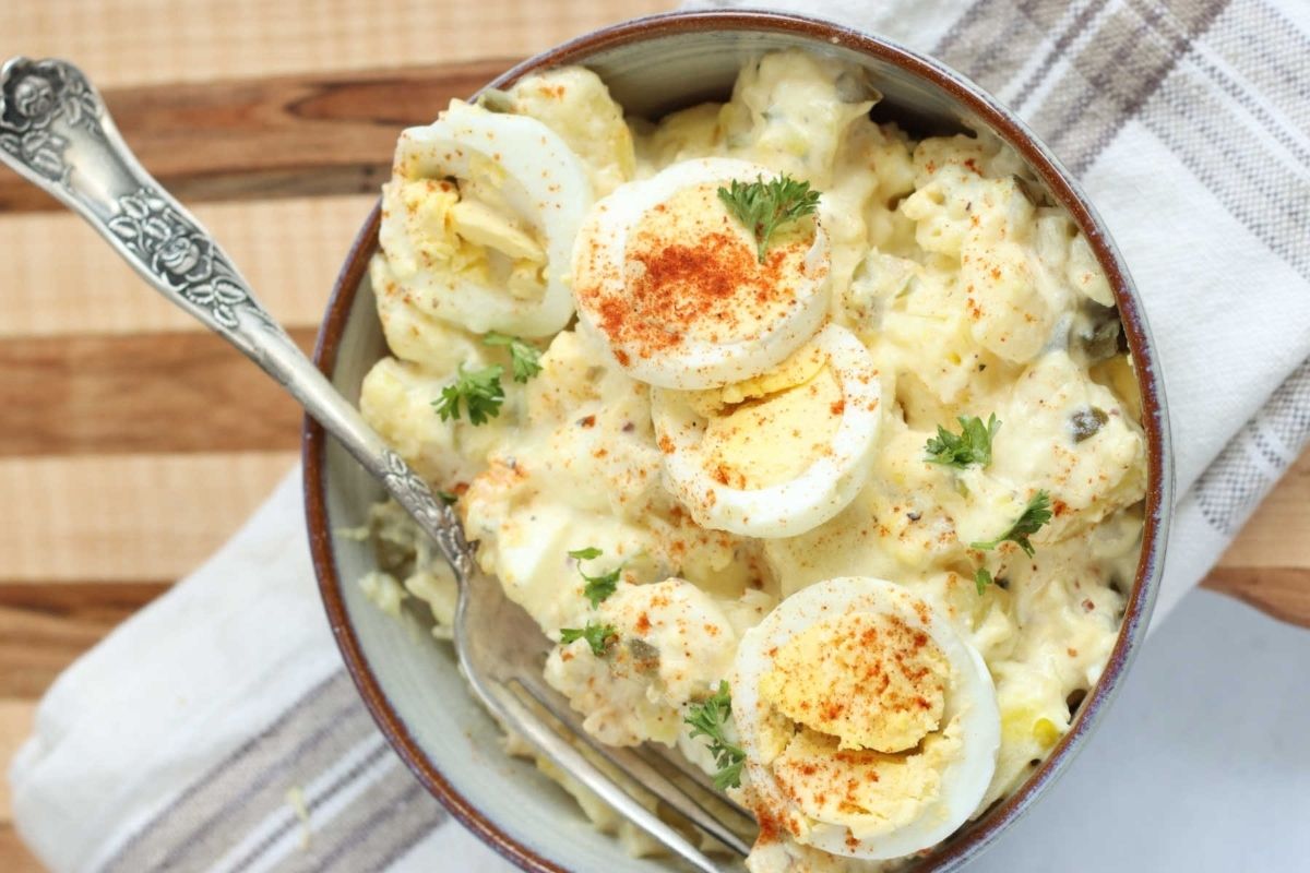 A bowl of mashed potatoes topped with eggs and parsley.