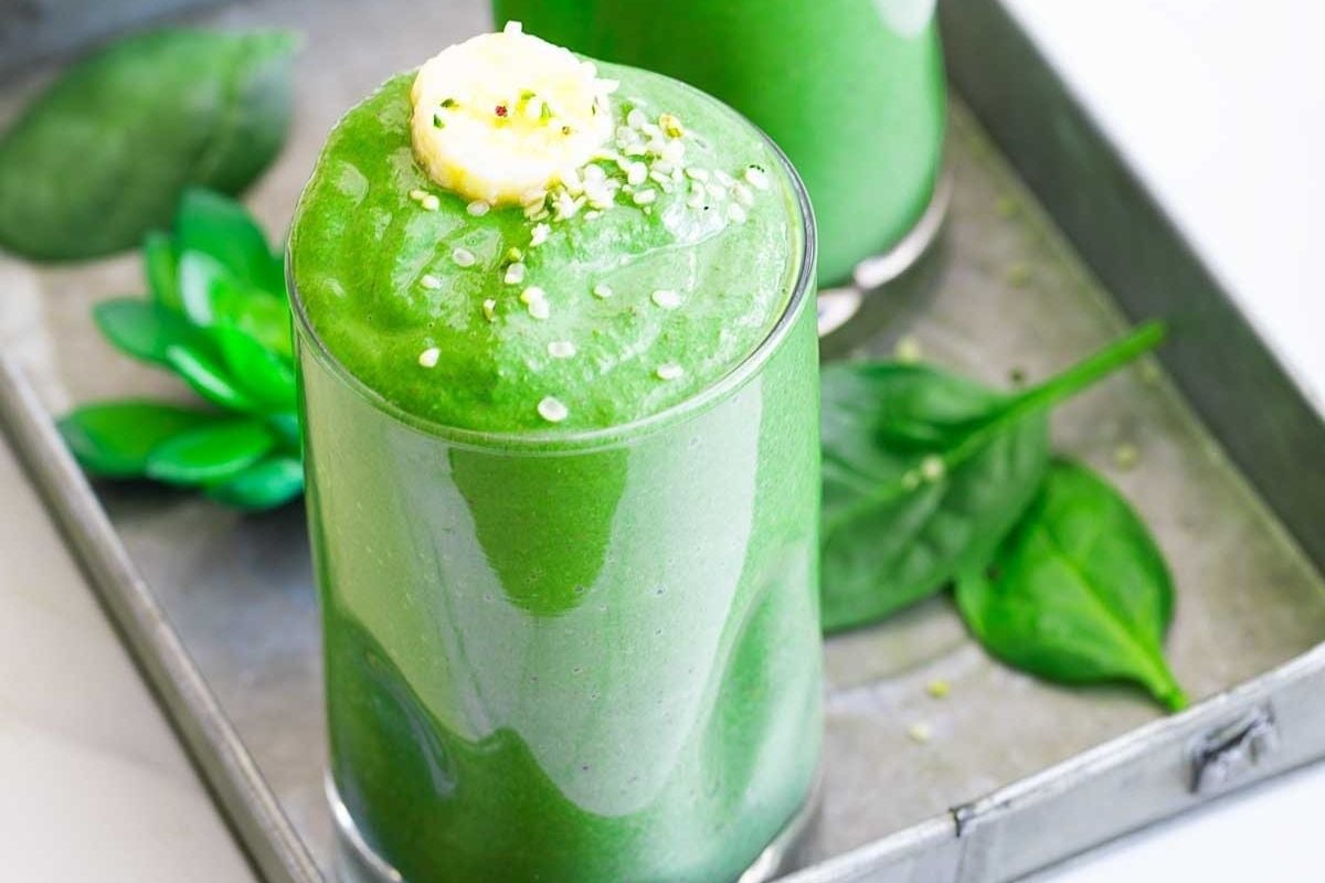 Two glasses of green smoothie on a tray with pinwheel recipes.