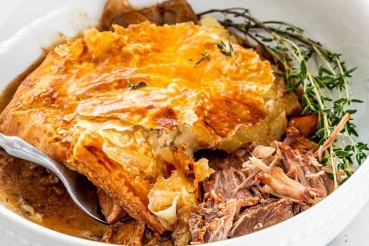 A warm bowl of meat pie __in winter__ with a spoon and thyme.