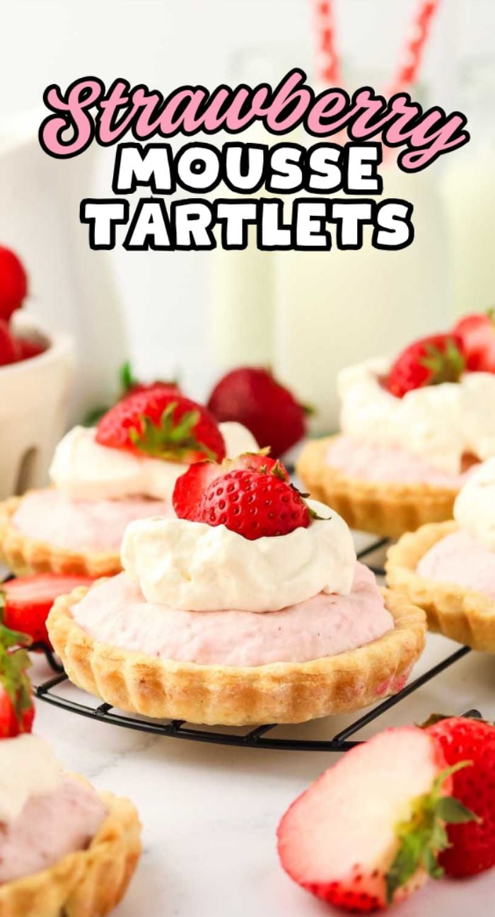 Strawberry Mousse Tartlets topped with whipped cream and fresh strawberries, beautifully displayed on a cooling rack.