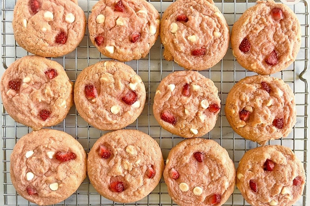 Pink strawberry and white chocolate cookies on a cooling rack.