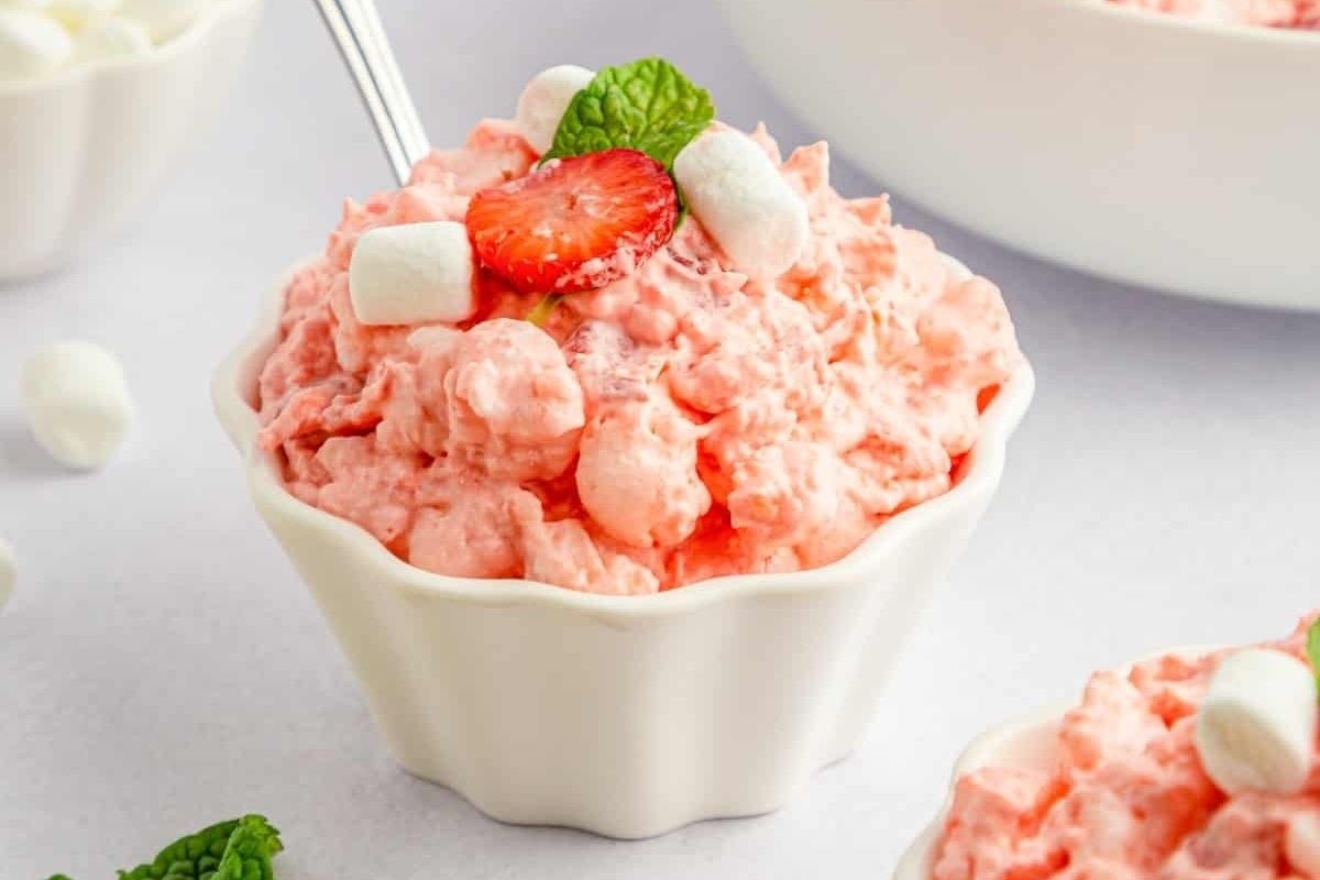 Strawberry ice cream in a pink bowl with a spoon.