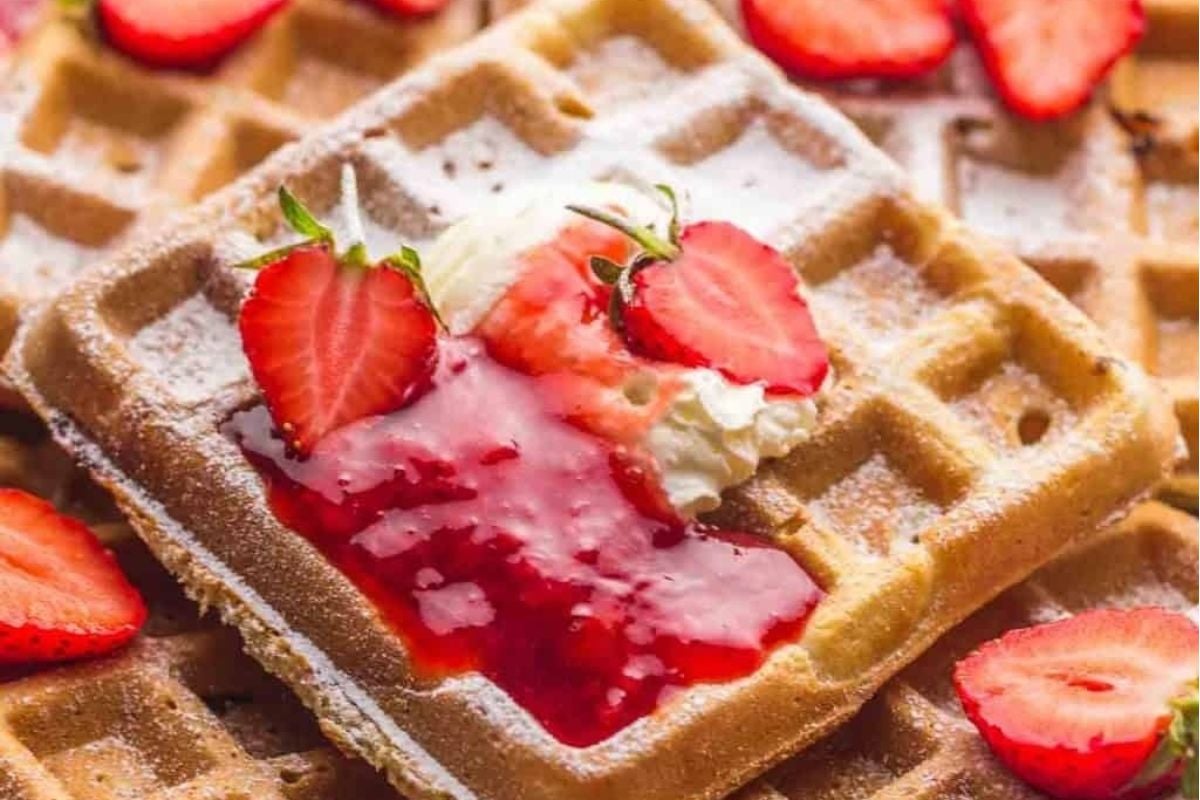 Waffle recipes with strawberries and cream on a white plate.