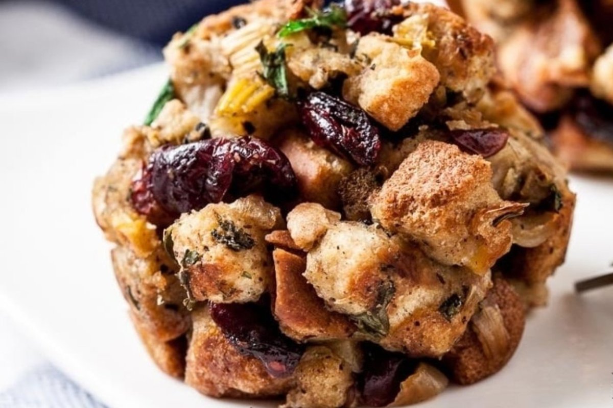 A close-up of a serving of savory muffins with herbs and dried cranberries.