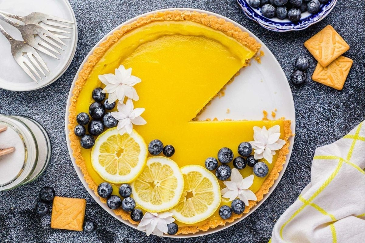 A citrus lemon tart with blueberries and lemon slices on a plate.