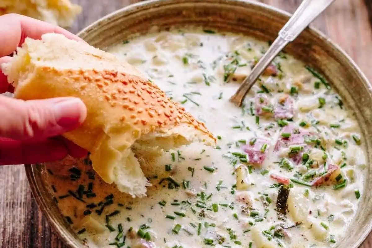 A hearty chowder recipe featuring a bowl of soup with crusty bread immersed in it.