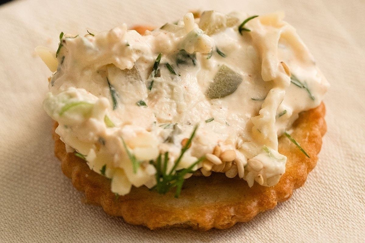 A cracker with cream cheese and dill on it, perfect for pickle lovers looking for new recipes.