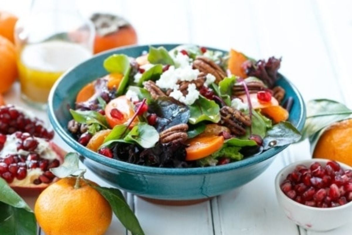 A bowl of salad with oranges and pomegranate, perfect for citrus lovers.