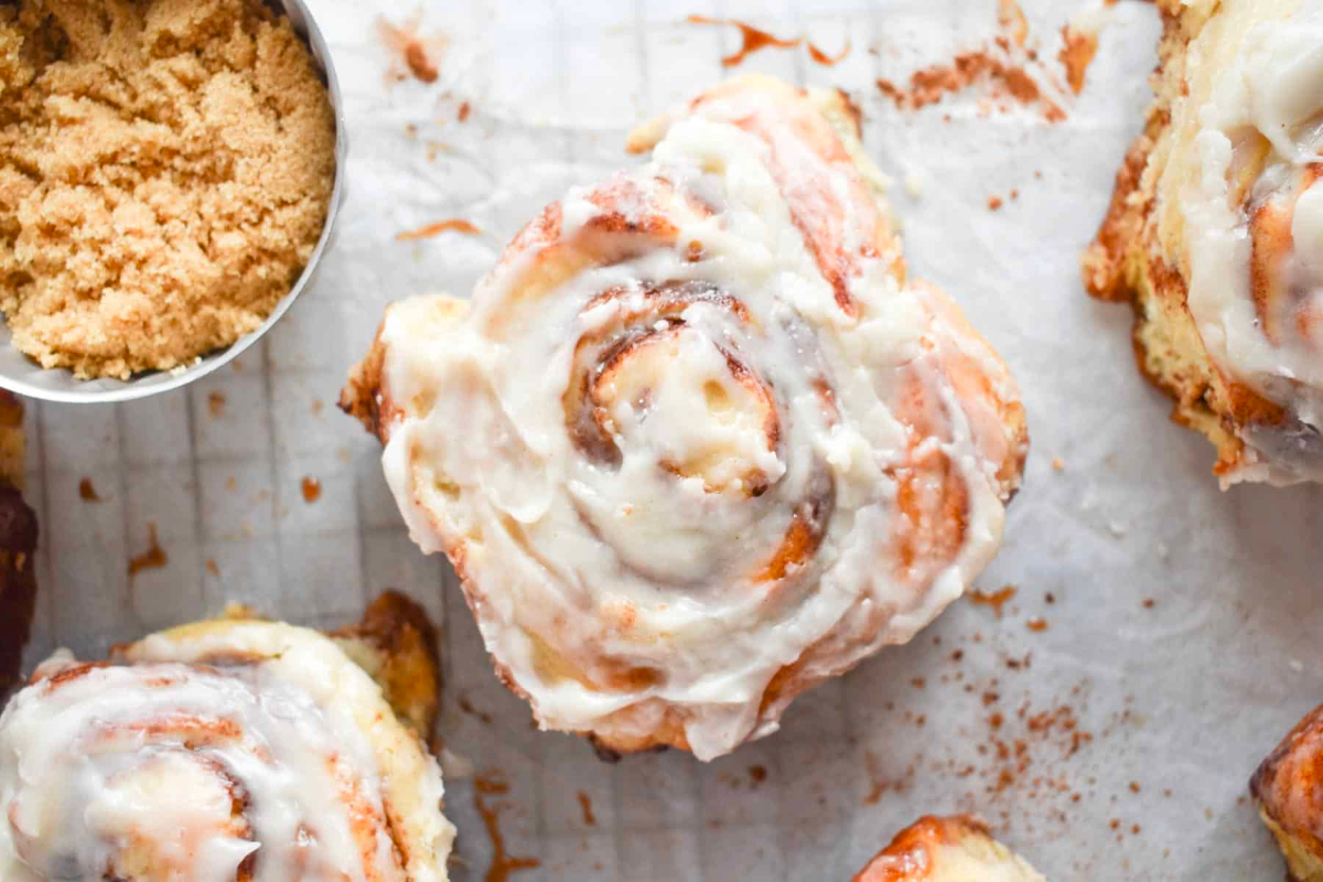 Delicious cinnamon rolls with icing and sugar on a baking sheet, made from scratch using a trusted cinnamon roll recipe.