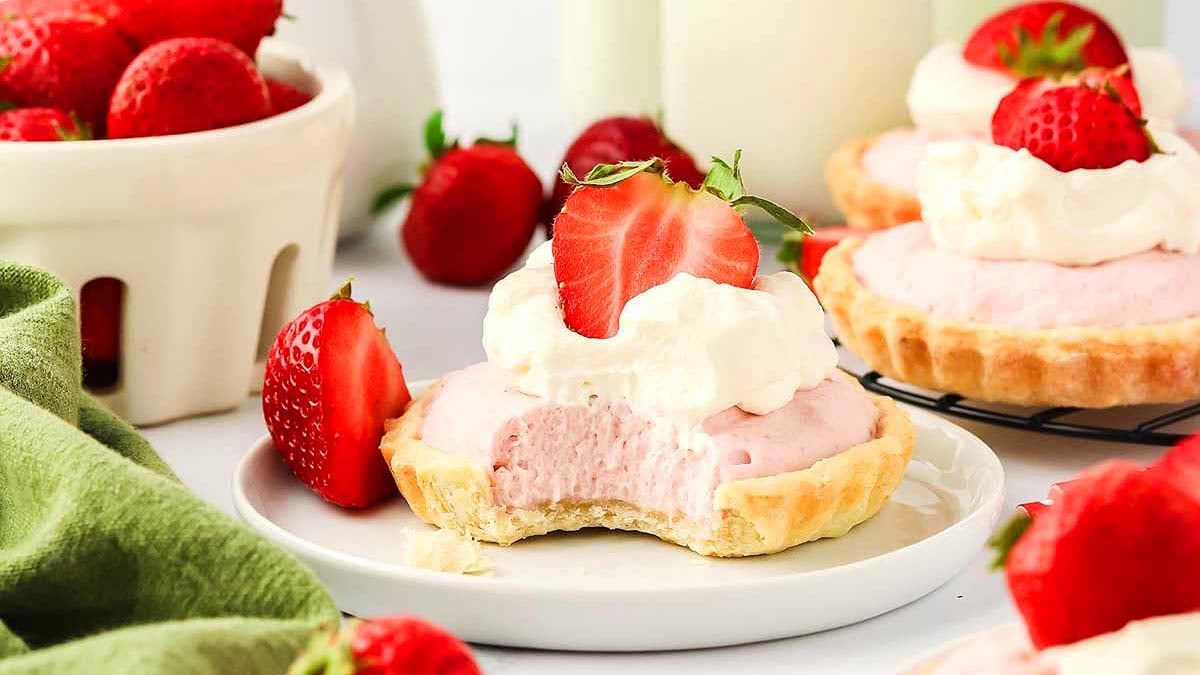 Strawberry tarts with whipped cream and strawberries on a plate.