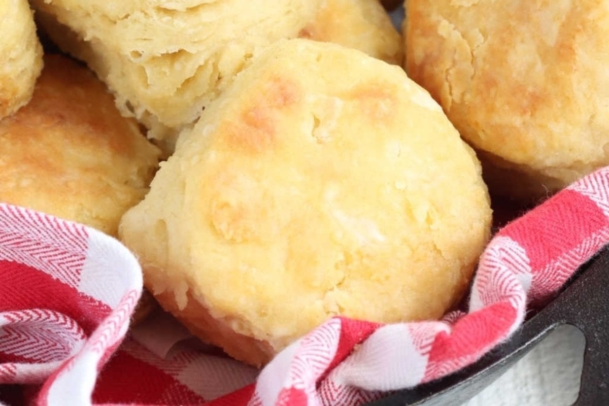 Close-up of freshly baked biscuits in a skillet, wrapped partially with a red and white patterned napkin, perfect for comfort food recipes.
