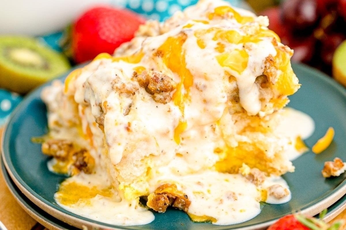 A slice of layered comfort food dessert with creamy topping and nuts, garnished with fruit zest, served on a blue plate.